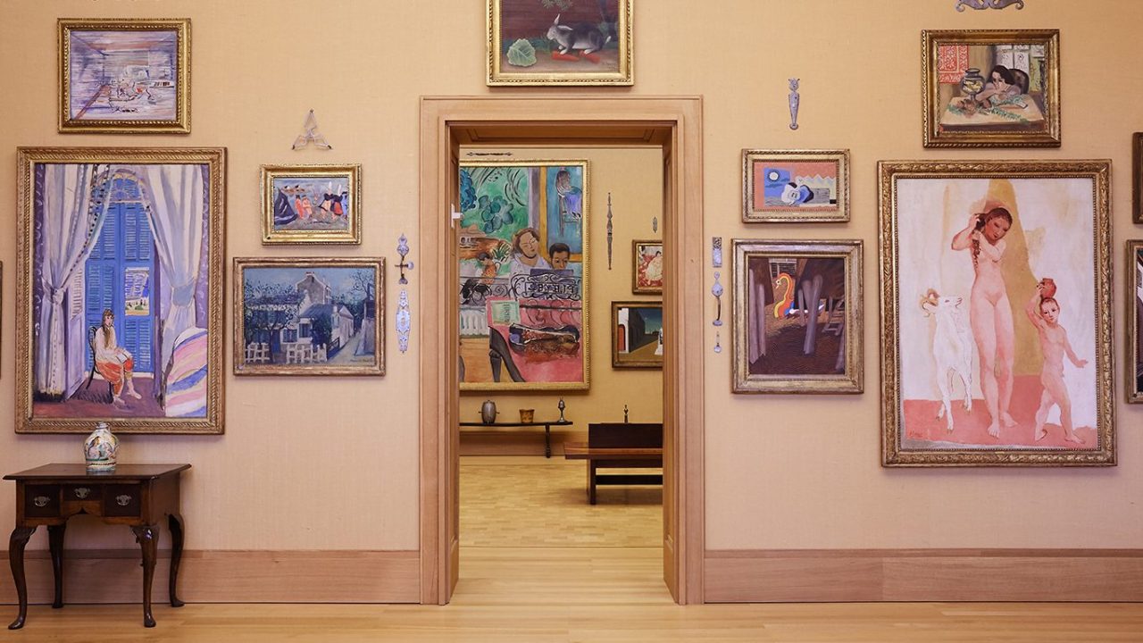 An interior view of the Barnes Foundation, with modern paintings hung on yellow walls