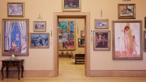 An interior view of the Barnes Foundation, with modern paintings hung on yellow walls
