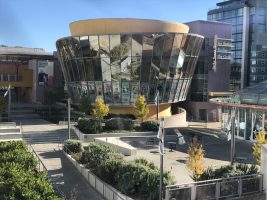 Exterior of the museum is a circular facade covered in glass/mirrors and a courtyard in front