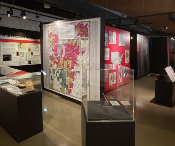 Photo of an exhibition - including display cases and a wall of map infographics