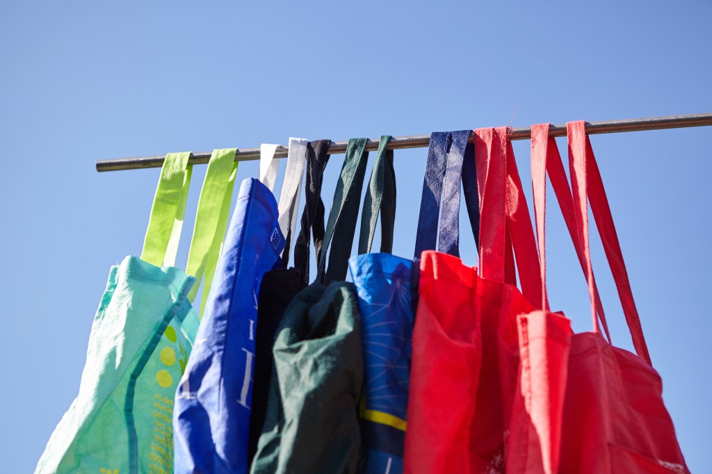 A low angle shot of colorful eco-friendly reusable cloth bags hanging on a pole