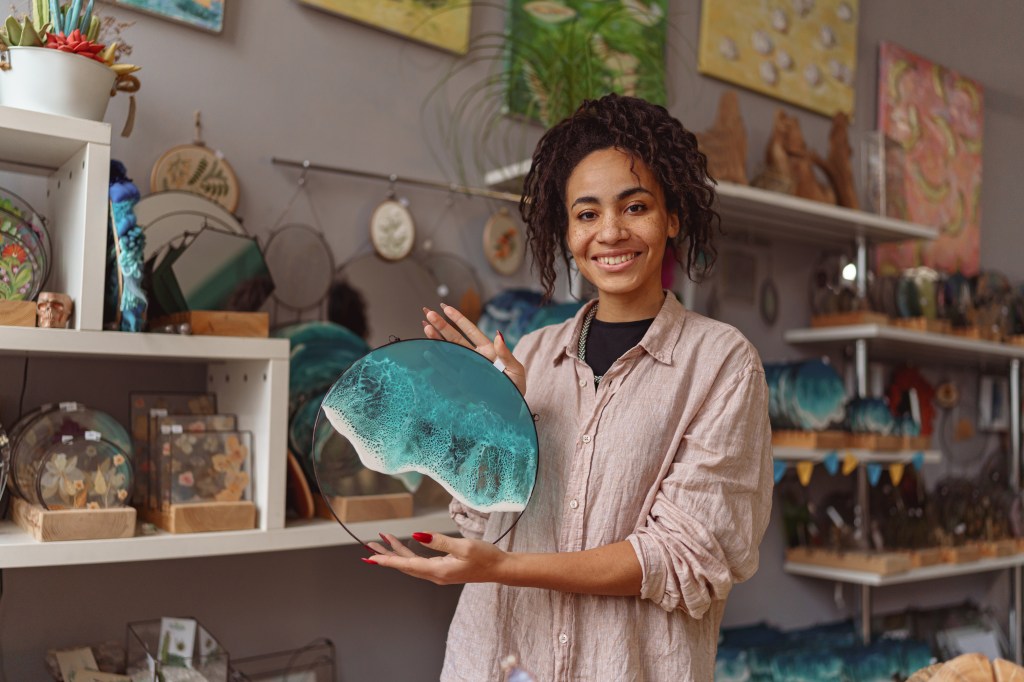 A person holding a holding handmade epoxy resin glass tray with sea waves