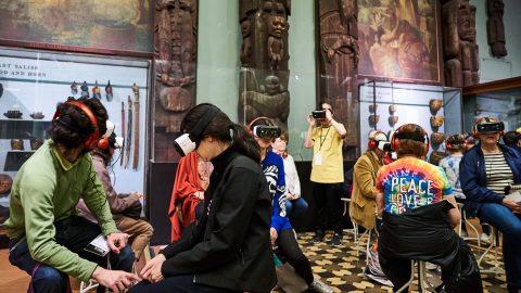 A group of young visitors using virtual reality goggles in a museum gallery