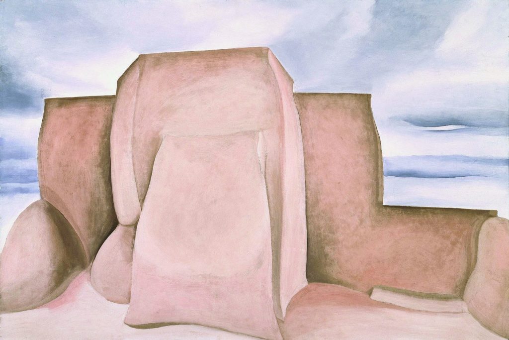 Georgia O'Keeffe's Ranchos Church, New Mexico, 1930-31, oil on canvas, Amon Carter Museum of American Art, Fort Worth, Texas. Two pink shaded structures stand against a streaky blue and purple sky. 