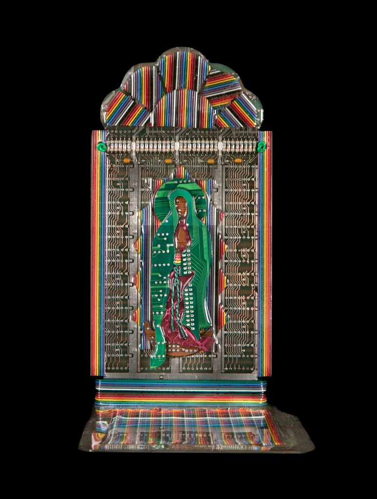 A sculpture resembling a microchip with rainbow stripes and a figure of the Virgin Mary carved inside
