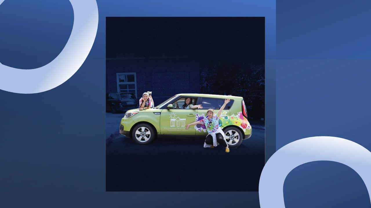 Three people stand behind, in front of, and inside a small green car decorated with Van Gogh art.
