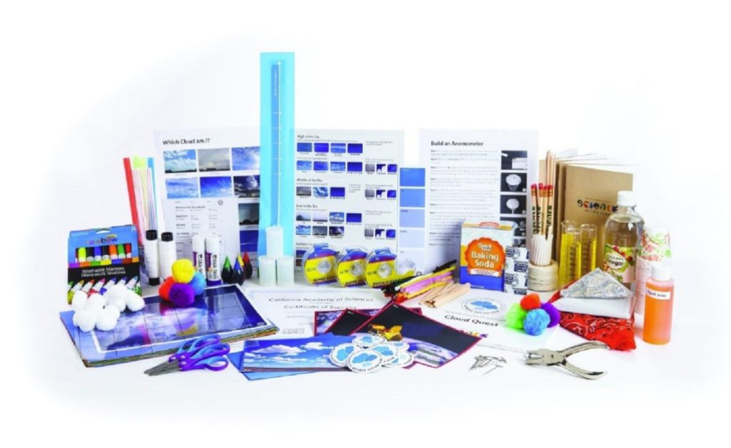 A science kit is displayed on a table with baking soda, colored pencils, and various other solutions. 