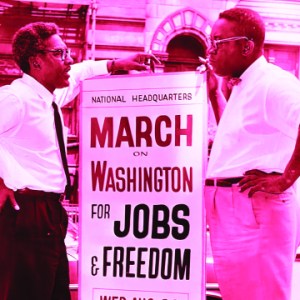 A historical image of two people standing beside a protest sign that reads "March on Washington for Jobs & Freedom"