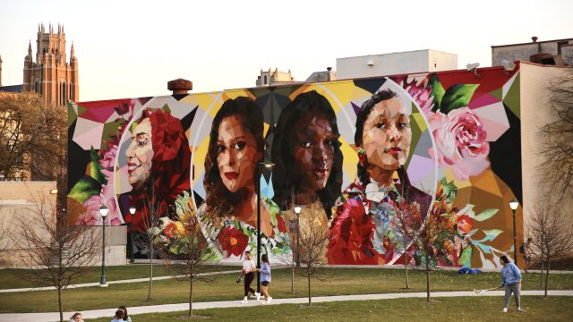 A large mural on the side of a building showing a diverse group of people through a kaleidoscope effect.