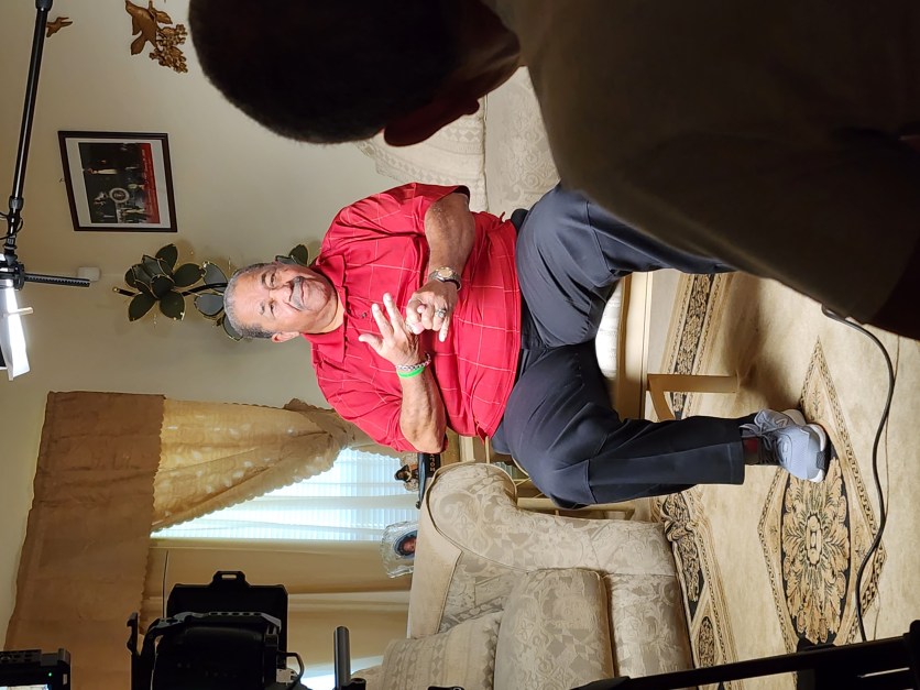An interview subject seated in front of a camera crew