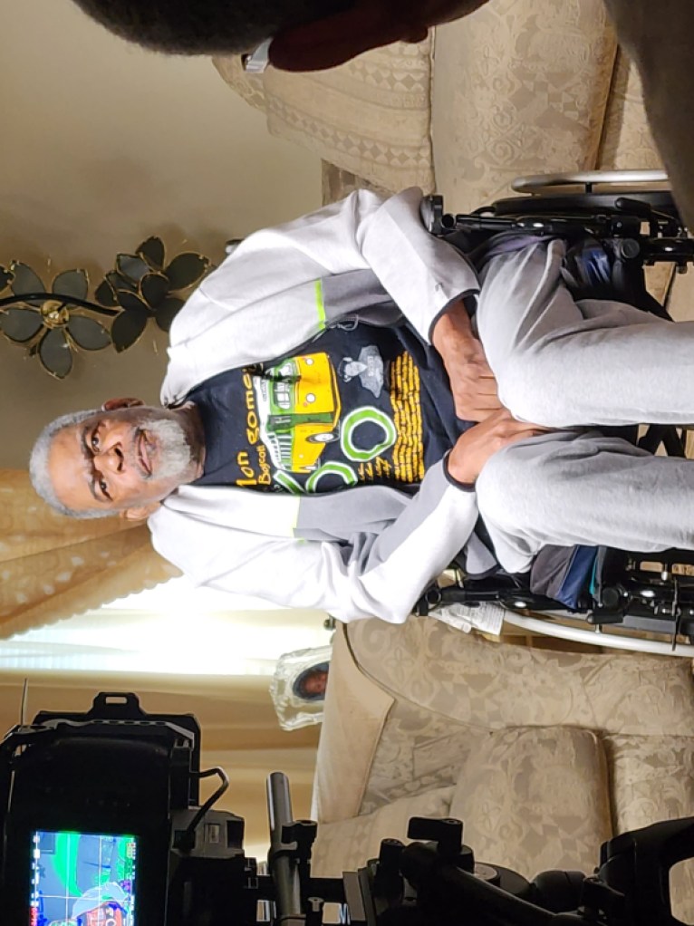 An interview subject seating in a wheelchair wearing a t-shirt commemorating the sixtieth anniversary of the Montgomery bus boycott