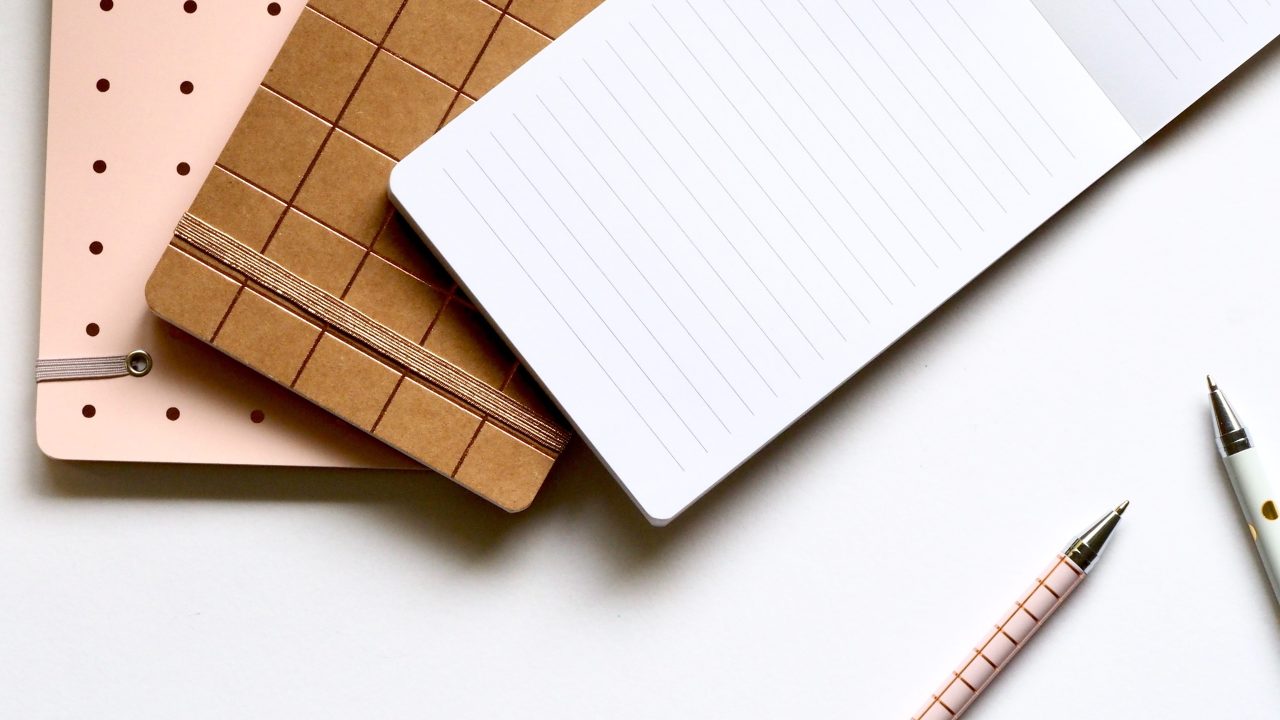 An array of notebooks and pens on a desktop