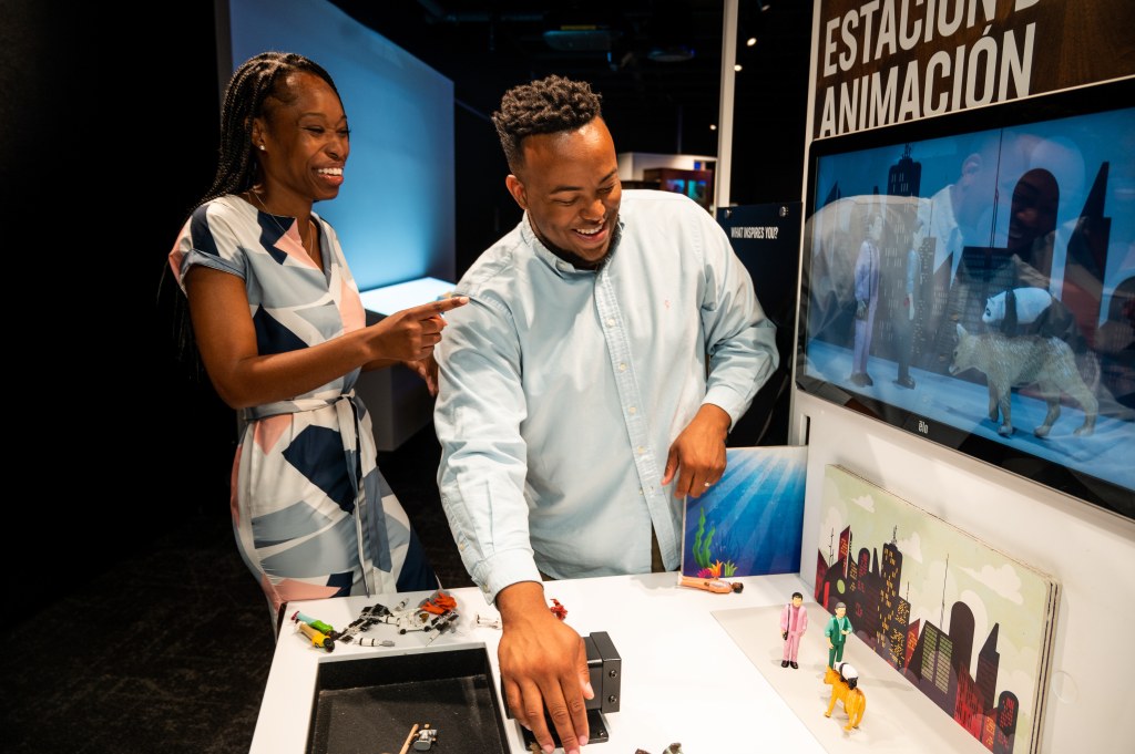 Two people playing with an interactive labeled "Estacion Animacion"