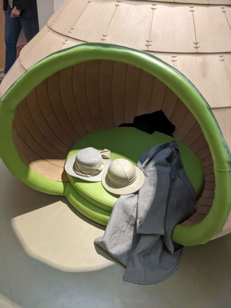 An igloo shaped structure with a large opening and two hats and a coat sitting on the top. 