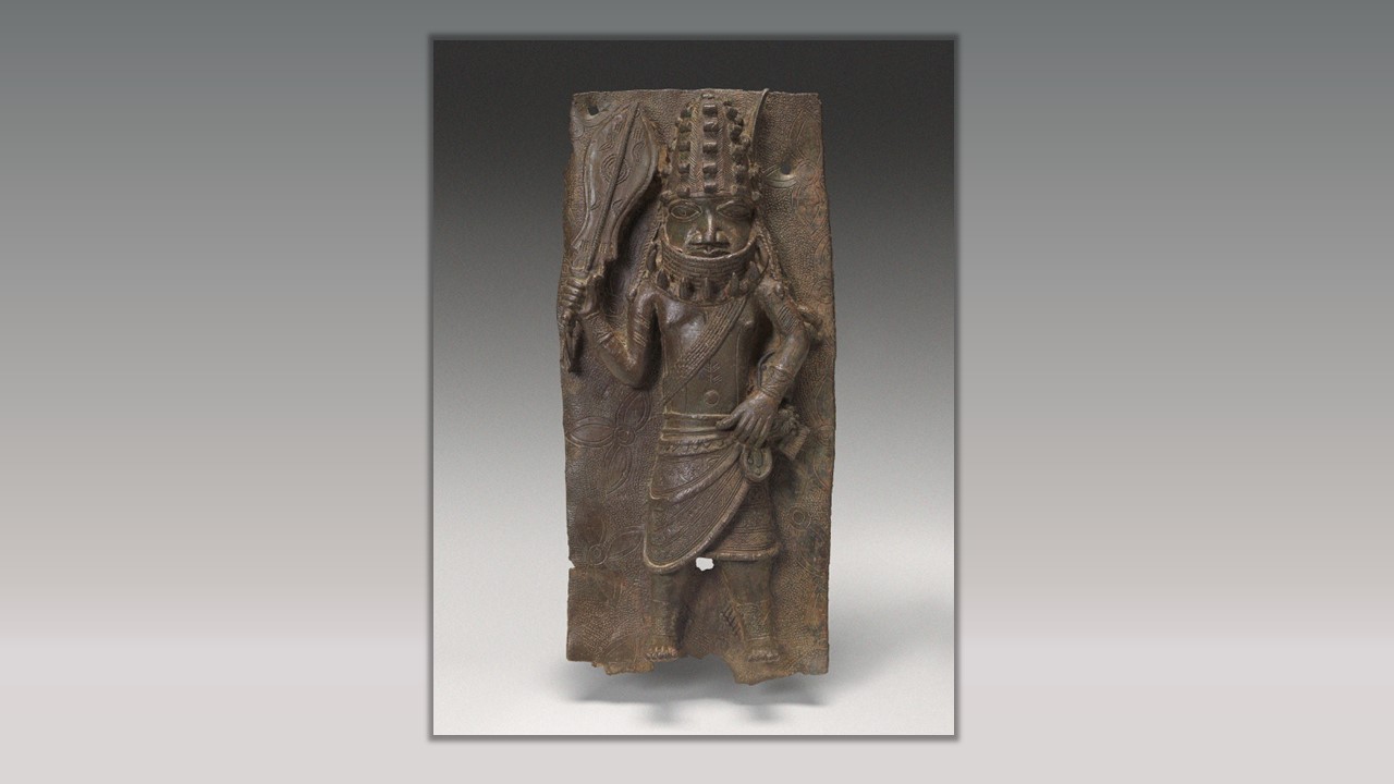 A Benin bronze of a warrior with a large machete like knife raised above it's head.