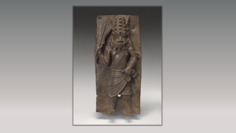 A Benin bronze of a warrior with a large machete like knife raised above it's head.