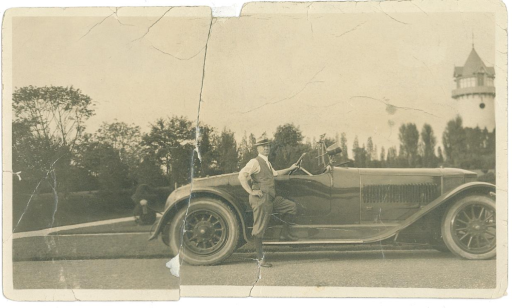 An antique photograph of Alfred I. duPont standing next to a vintage automobile at Nemours Estate.