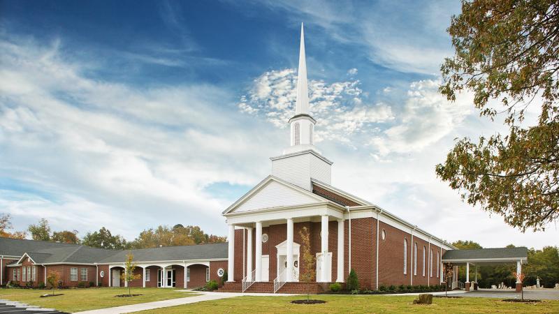 Exterior of a church with a large white steeple.