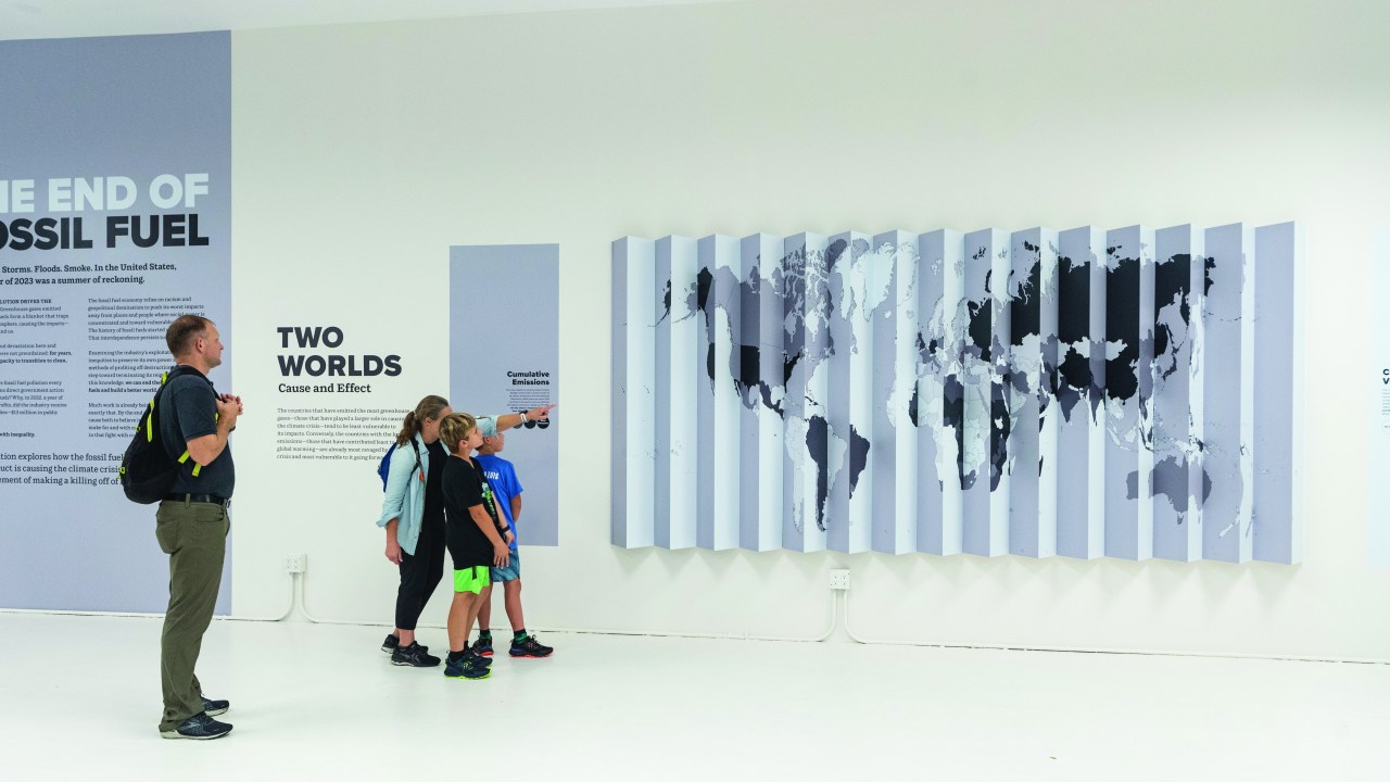 A group of people look at a map that is strategically cut in horizontal strips on a wall.
