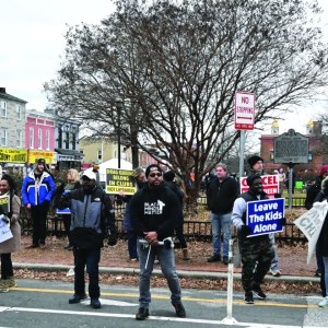 A group of demonstrators congregate on a street with several signs. 