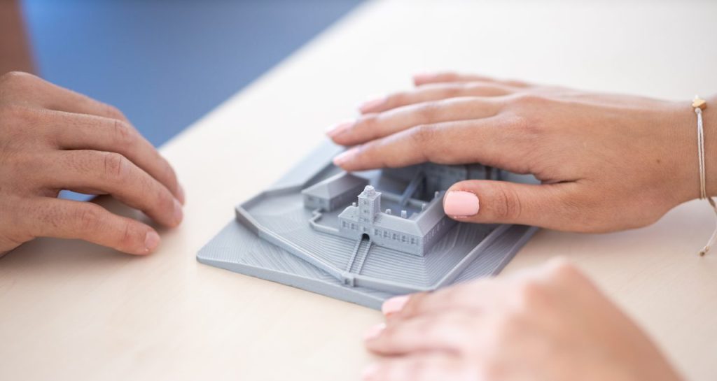 A pair of hands exploring a tactile model of a town