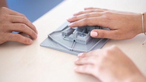 A pair of hands exploring a tactile model of a town