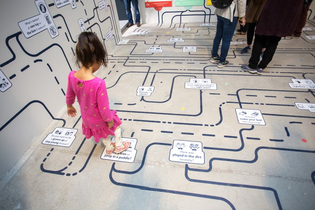 A child stands on top of a map that is painted on the floor and walls.
