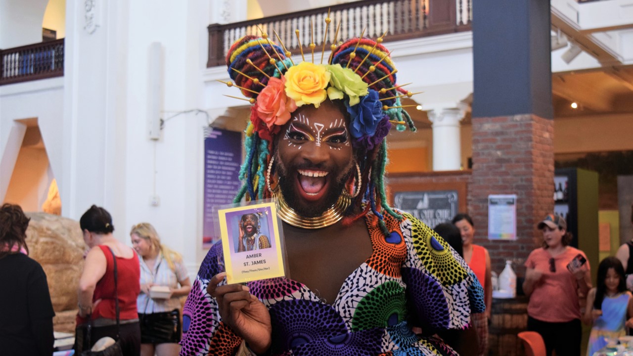 A joyful person stands with ta name badge.