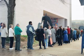 A crowd of people in line outside of a museum