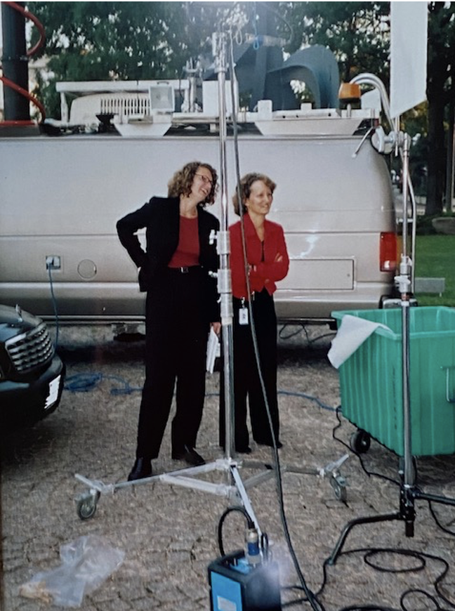 Two people standing next to a van with a camera