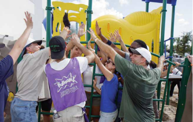 A group of volunteers help erect a piece of playground equipment.