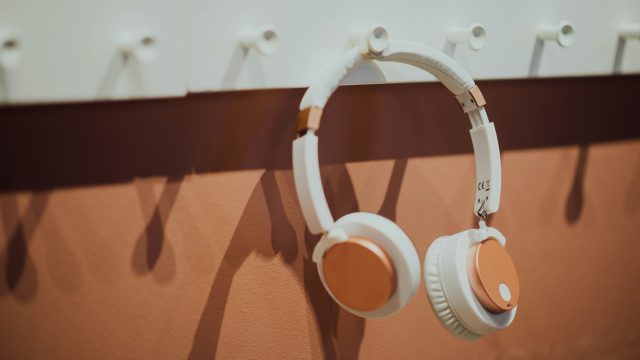 A pair of over-ear headphones hanging on a rack.