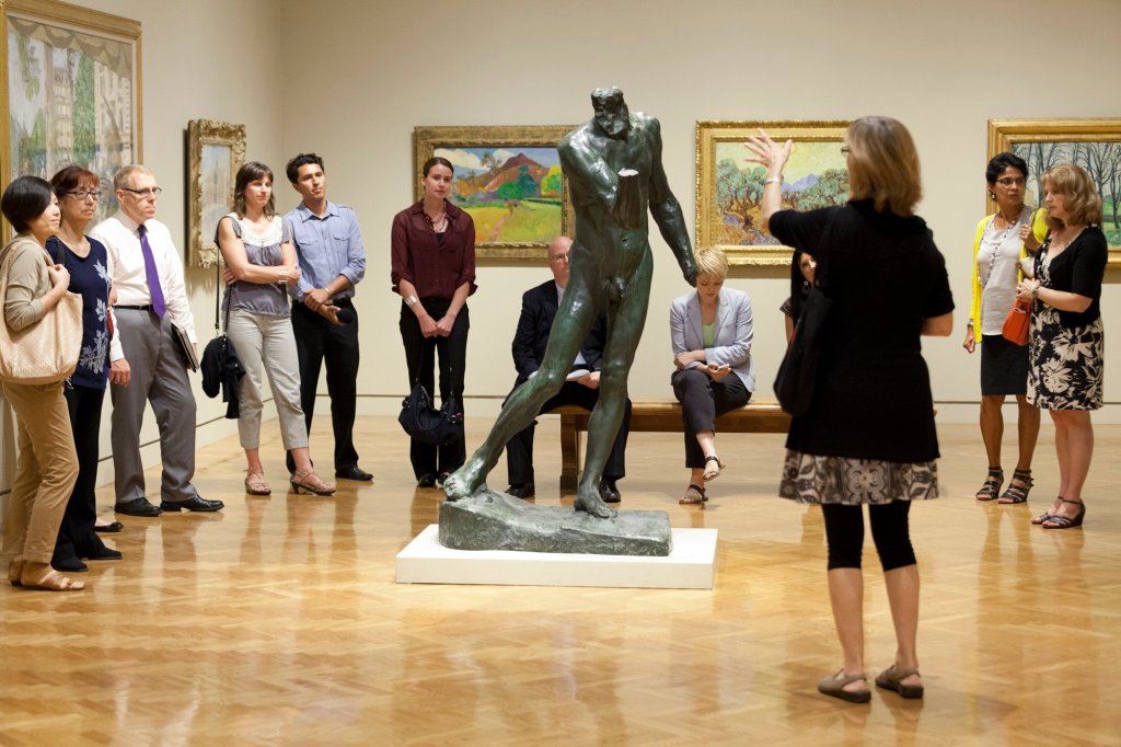 A group of people standing around a statue in a museum.