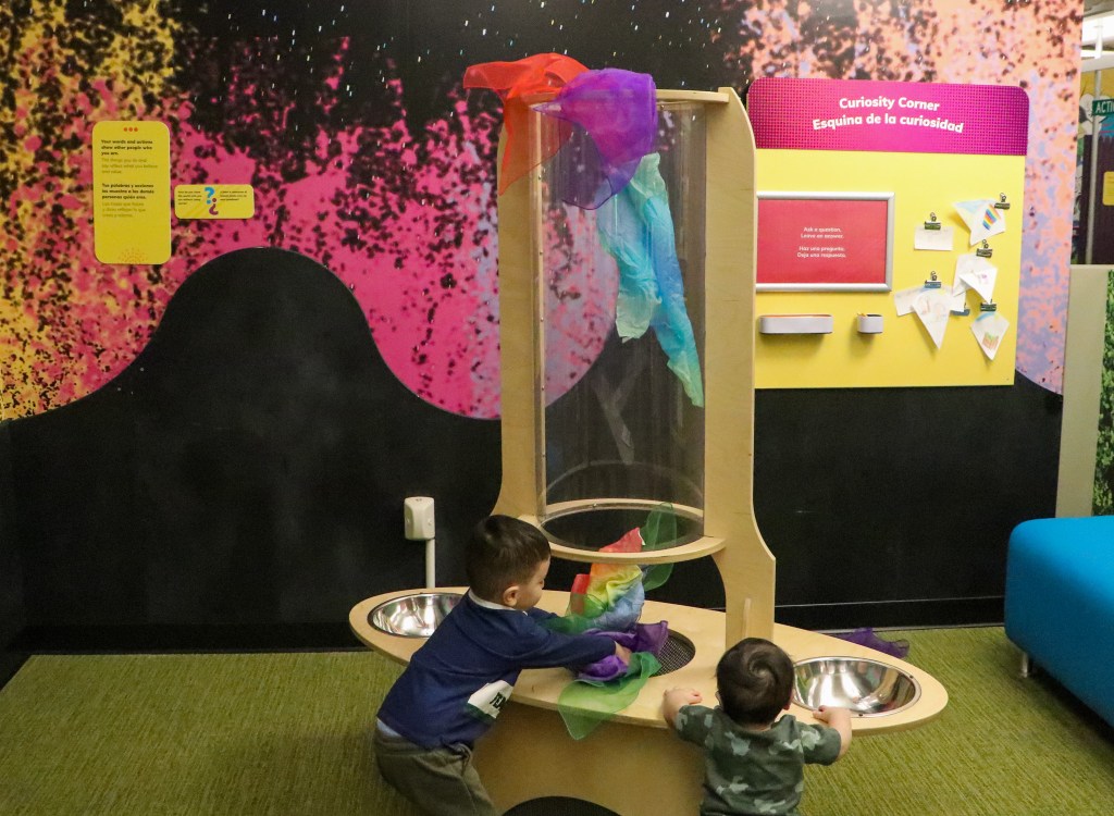 Two children enjoying an interactive play table at a museum