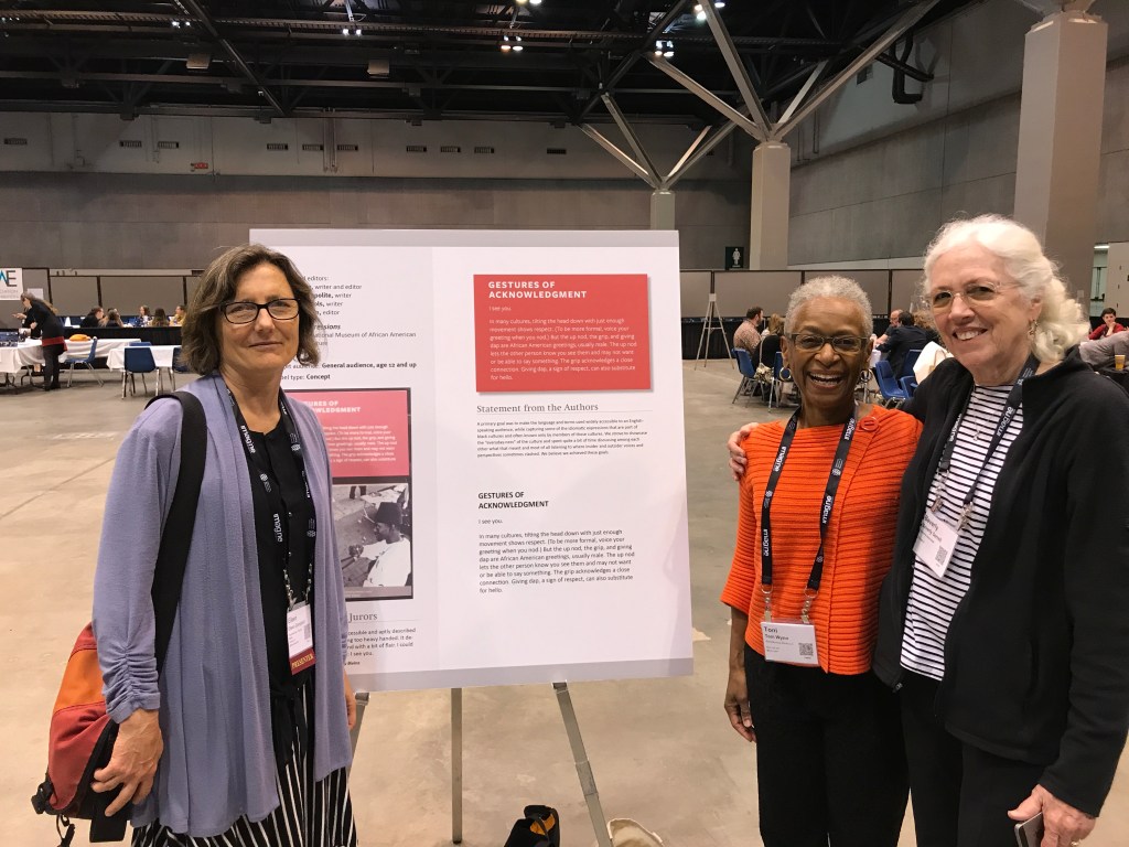 Three individuals standing around a poster, smiling.