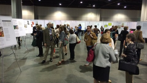 A group of people gathered at the annual meeting, surrounded by various posters.