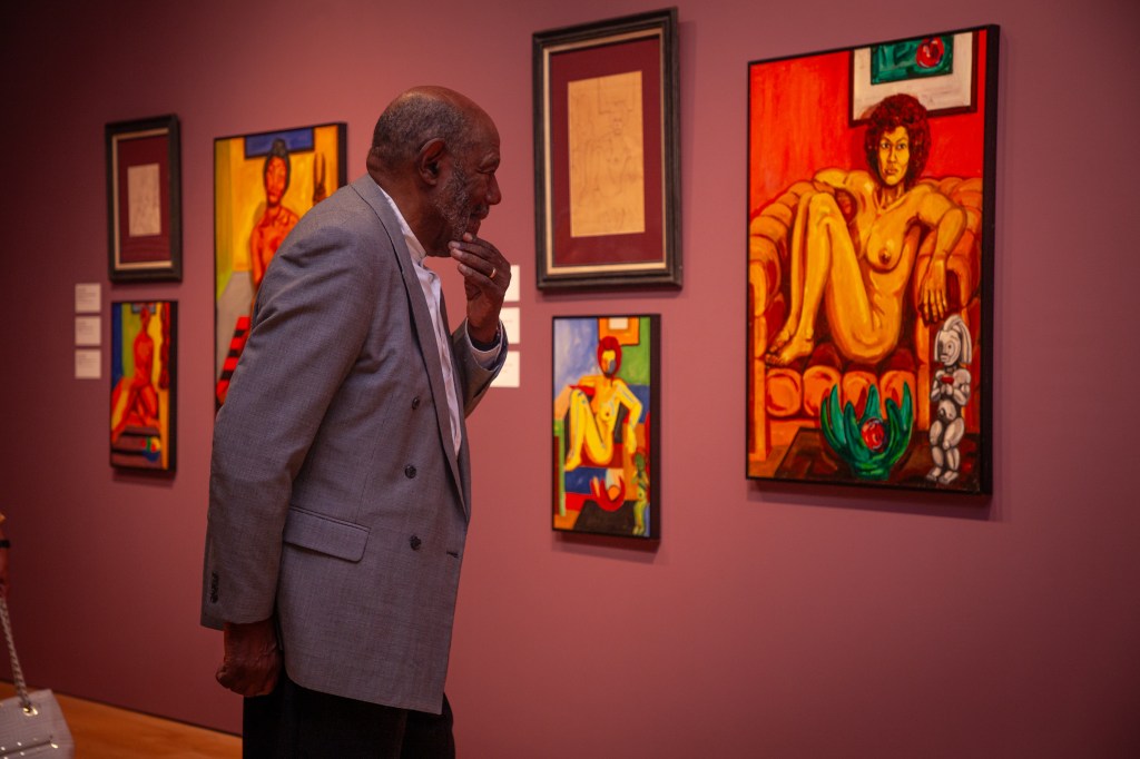 A person looking at a painting of a human figure in an art gallery.