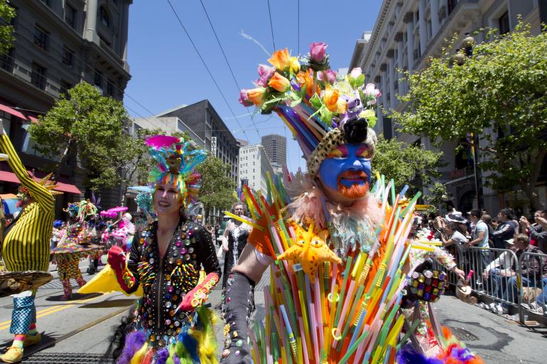 Two individuals in colorful costumes walking in a parade.