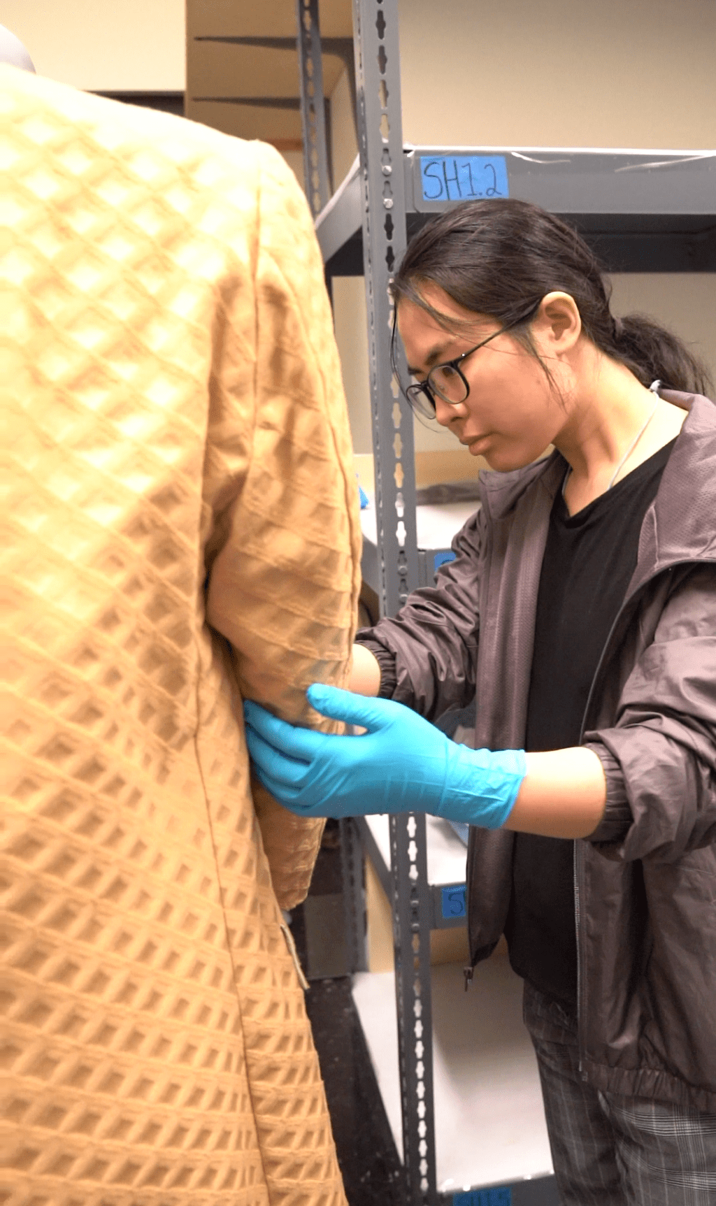 A person handling the sleeve of a coat in a storage space