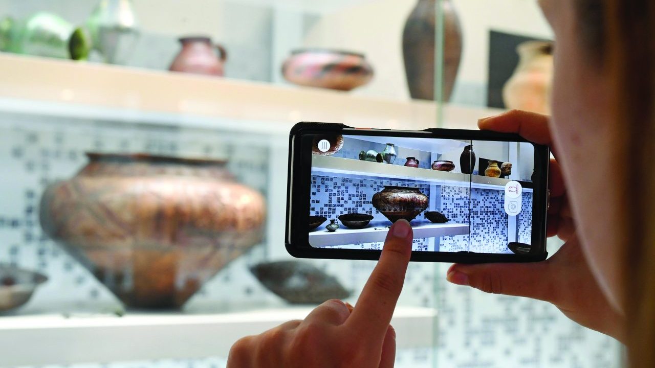 A person taking a picture of objects in a museum display case