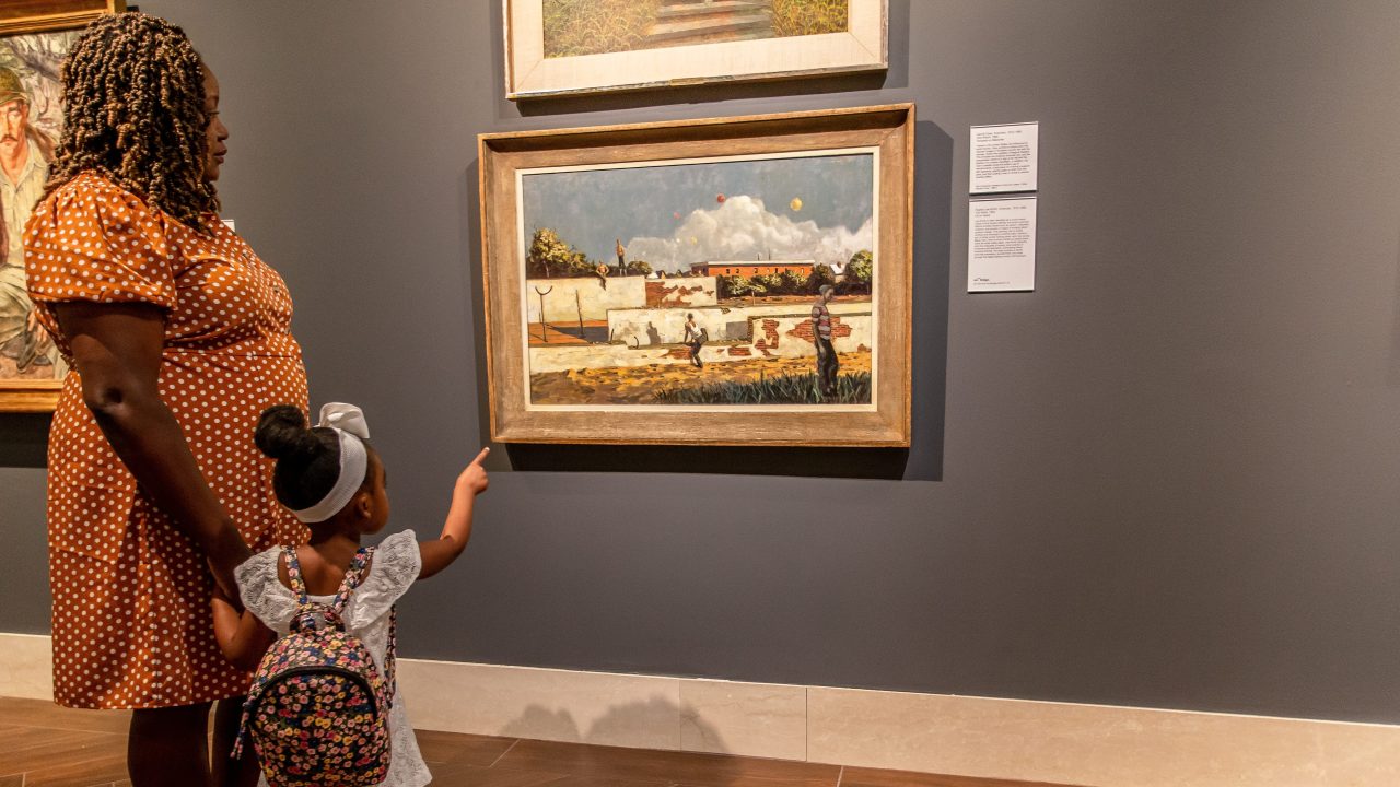 A child and adult looking at a painting in a museum gallery