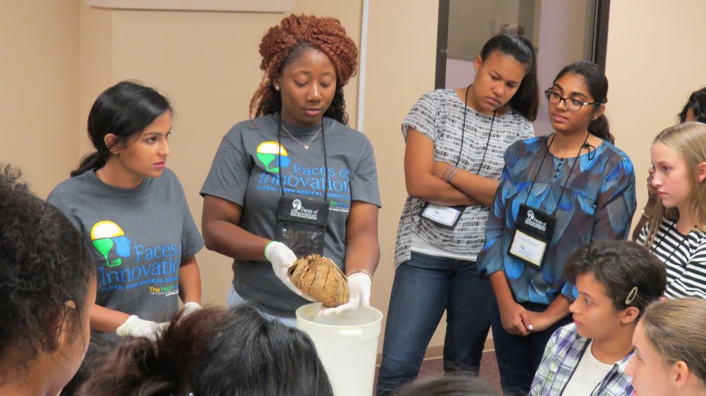 An instructor holding a brain with gloves while students watch