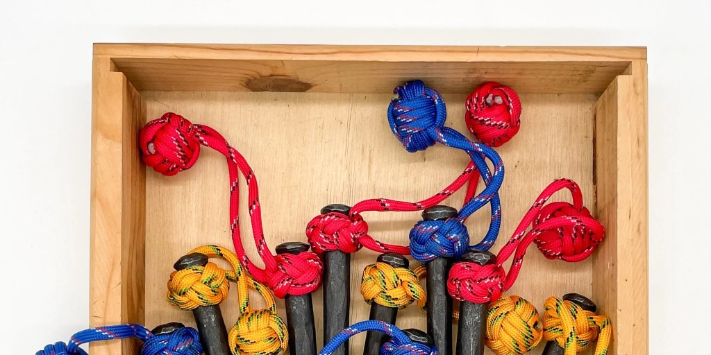A collection of iron spikes with paracords of different colors tied around the ends