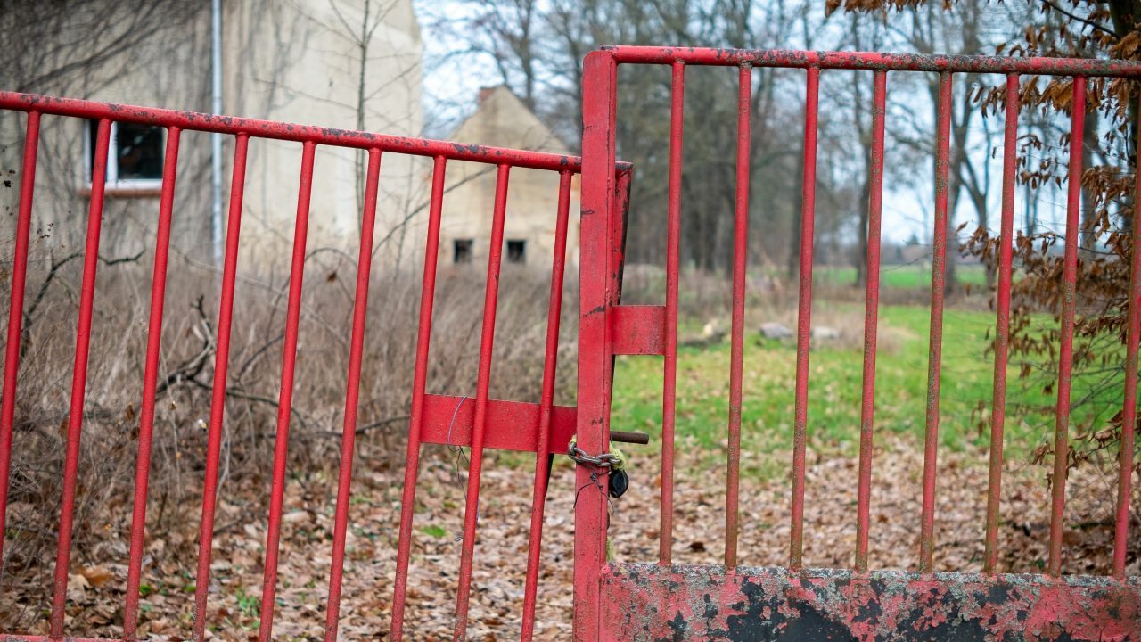 Closed and chained broken red gate in a farm