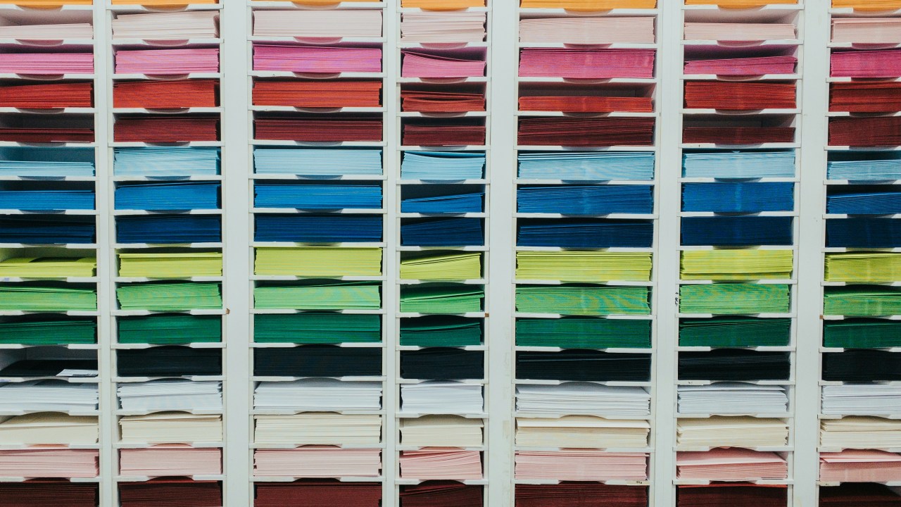 A shelving system full of stacks of multicolored paper