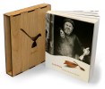 View of the Midcentury Master book with an image of Emil Milan on the cover with the book "sleeve", a wooden cover for the book with an embossed bird on the front, to the left hand side. 