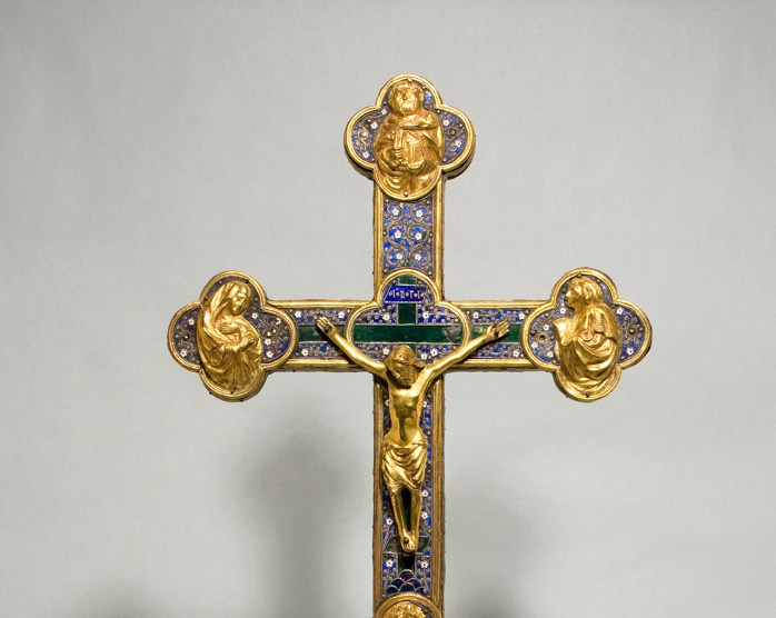 An ornate crucifix made of gold, enamel, and other materials on a long base