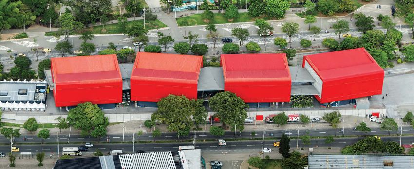 Four rectangular structures connected by gray passthroughs with red roofs sit in a stark landscape.