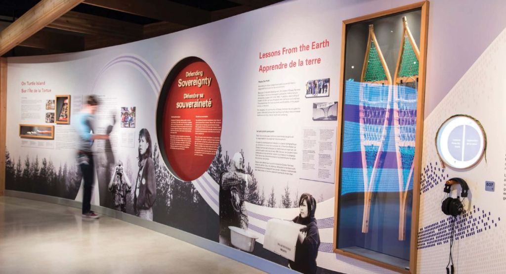 A large wall panel in the exhibit has a snow shoe encased and various black and white images