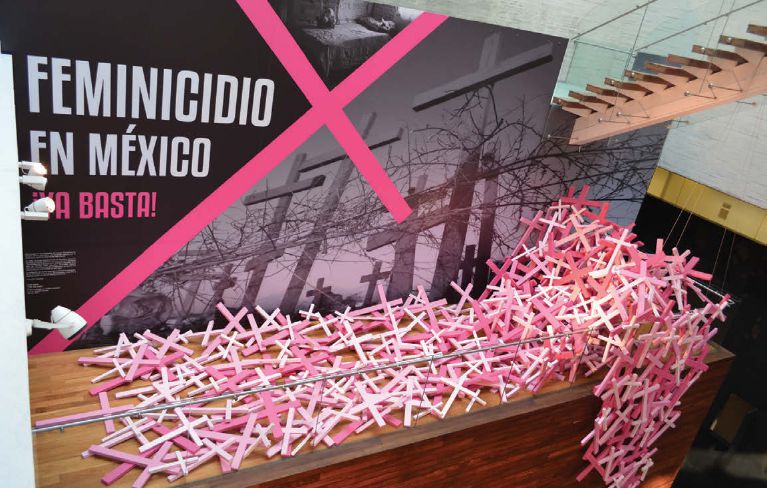 Small pink and white sticks line up in front of a text panel in the exhibition.